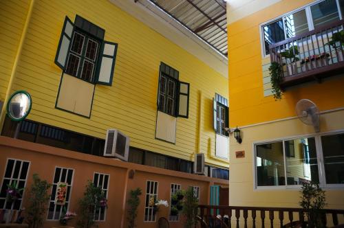 a yellow building with windows and a balcony at Samsen Sam Place in Bangkok