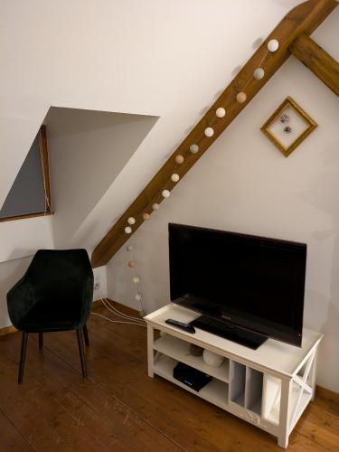 a living room with a tv and a chair at Les Toits de Turckheim in Turckheim