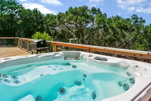 a jacuzzi tub on a deck with trees at Blue Spring Retreat in Wimberley