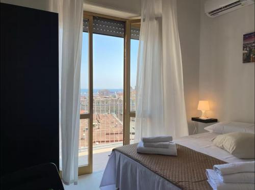 a bedroom with a bed and a large window at A cartulina e Napulè Attico con Vista Porto Ascensore Colazione Inclusa Struttura nel cuore autentico di Napoli a 5 minuti dalla Stazione Centrale e dal Centro Storico AC in Naples