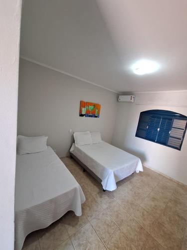 a room with two beds and a window in it at Pousada DONA DUTRA in Lençóis Paulista