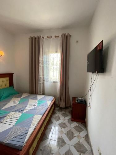 Un dormitorio con una cama y un televisor de pantalla plana. en Résidence T&M, en Méhandan
