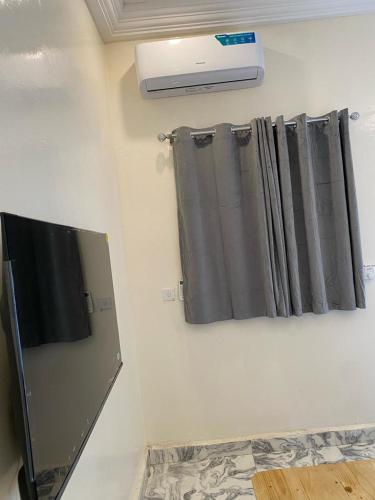 a room with a curtain and a television on a wall at Grumpy Awa in Sere Kunda