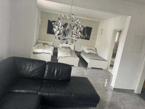 ホーフハイム・アム・タウヌスにあるBenk 24H Apartment Nr 1 Perfekt für bis zu 6 Personenのリビングルーム(黒い革張りのソファ、シャンデリア付)