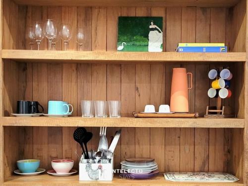 a wooden shelf with dishes and cups and utensils at Casa - Centro Px Matriz c/ Churrasqueira, 2 Suítes in Poços de Caldas