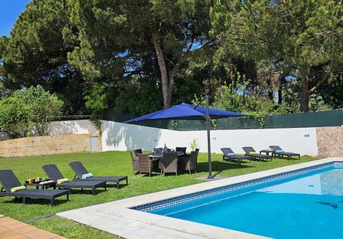 a swimming pool with lounge chairs and an umbrella next to it at 4 suites, piscine, Casa Rio-Dora by SesimbraSunSea in Lagoa de Albufeira