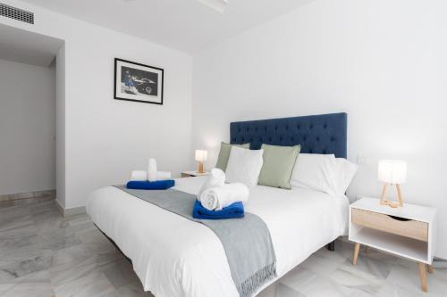 a bedroom with a large white bed with blue accents at 3D MTR - Marbella Temporary Rent Two Bedrooms Apartment Marbella Old Town in Marbella