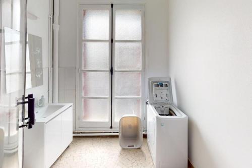 une salle de bains blanche avec un lave-linge et une fenêtre. dans l'établissement F3 - Rue Dauphine, au Havre