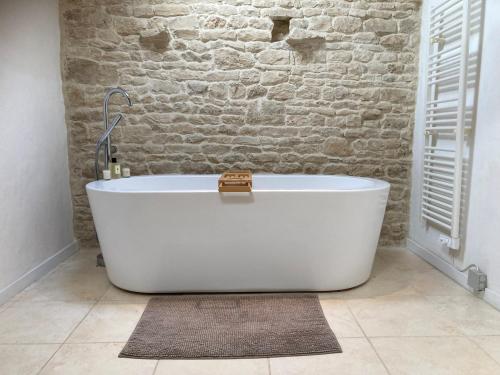 Una bañera blanca en un baño con una pared de ladrillo. en Rural 3 Bedroom Gite with Swimming Pool, en Raix