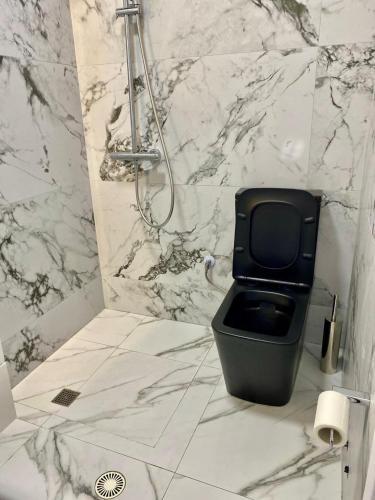 a bathroom with a black toilet and a marble wall at Cambel Luxury Apartment in Sarandë