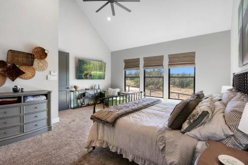 a bedroom with a bed with a dresser and windows at Here Comes the Sun in Canyon Lake