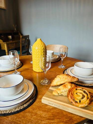 a wooden table with plates and glasses and bread at Comfy 3 Bedroom Home Free Parking in Doncaster in Balby