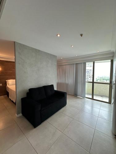a living room with a black couch and a bed at Mediterrâneo flat 1309 in Rio de Janeiro