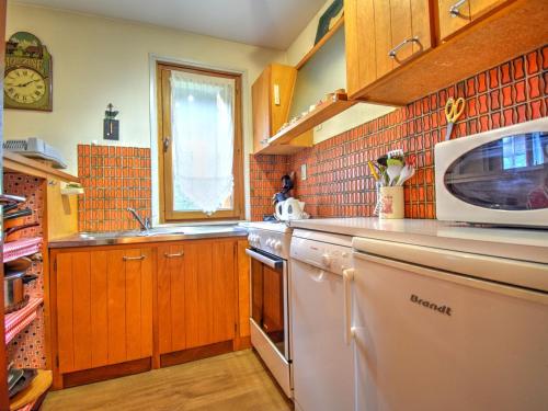 une cuisine avec un micro-ondes et une cuisinière four supérieur dans l'établissement Appartement 3 pièces proche centre et pistes, animaux admis, parking privé - FR-1-524-34, à Morzine