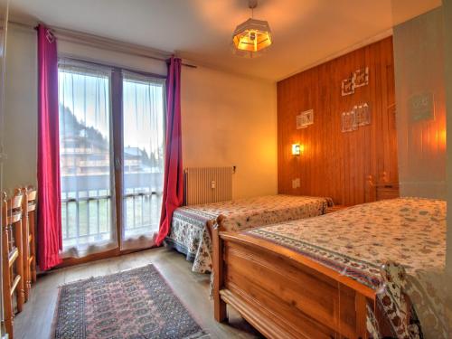 une chambre avec deux lits et une grande fenêtre dans l'établissement Appartement 3 pièces proche centre et pistes, animaux admis, parking privé - FR-1-524-34, à Morzine