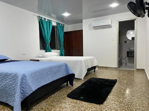 a bedroom with two beds and a window and a rug at HOTEL GANADERO in La Dorada