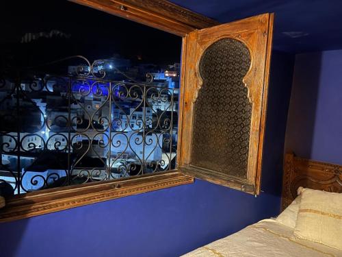 a bedroom with a window with a iron fence at Dar Nakhla in Chefchaouene