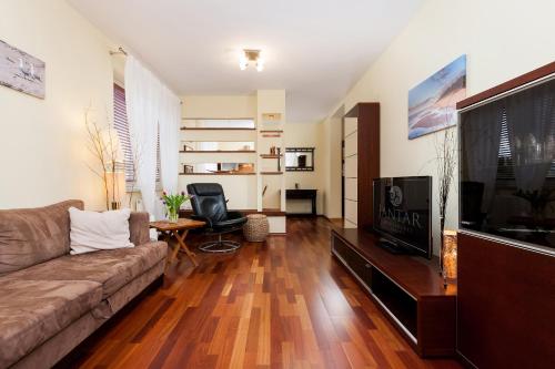 uma sala de estar com um sofá e uma televisão de ecrã plano em Jantar Apartamenty- Zielone Tarasy em Colberga