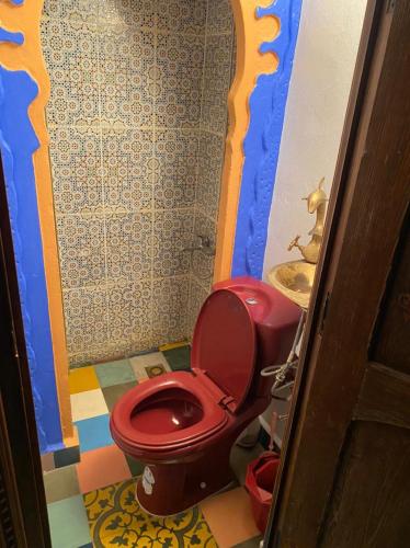 a bathroom with a red toilet and a sink at Dar Nakhla in Chefchaouene