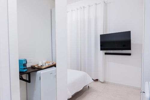 a white room with a desk with a tv and a chair at Duomo Rooms - Manfredi Homes&Villas in Manfredonia