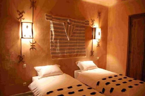 two beds in a room with lights on the wall at Terres d'Amanar in Tahannout