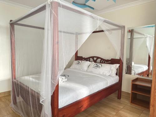 a bedroom with a canopy bed with white sheets and pillows at Maanet Gardens Hotel in Kutu