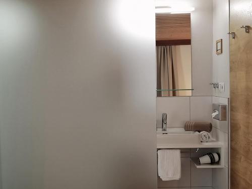 a white bathroom with a sink and a mirror at Huber - Das Tiroler B&B in Oberperfuss
