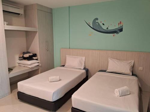 a room with two beds and a shelf with towels at Glossy Marina Homestays in Lumut