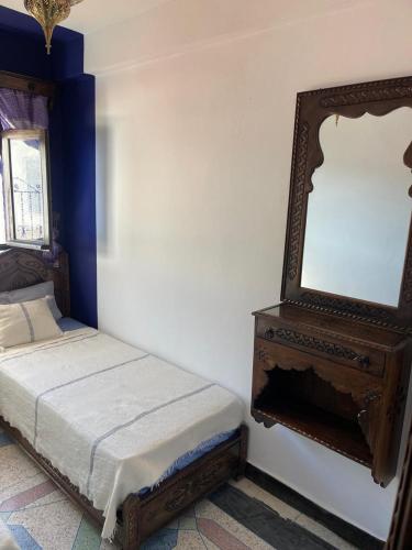 a bedroom with a bed and a mirror on the wall at Dar Nakhla in Chefchaouene
