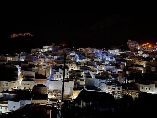 a city lit up at night with white buildings at Dar Nakhla in Chefchaouene