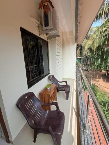 a balcony with two chairs and a table and a window at Whispering Waves Luxury Homes in Majorda