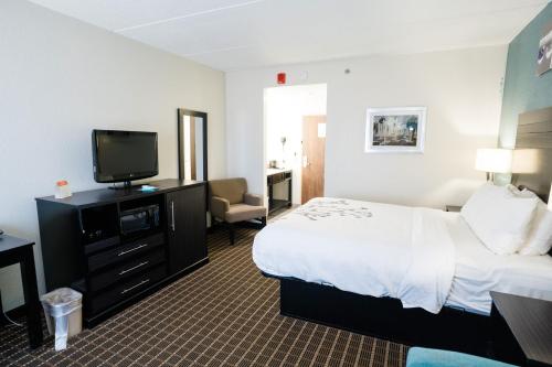 a hotel room with a bed and a flat screen tv at Sleep Inn & Suites West Knoxville in Knoxville