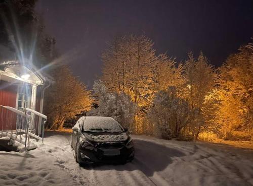 une voiture garée dans la neige à côté d'une maison dans l'établissement Vinterhus nära Romme Alpin, à Borlänge