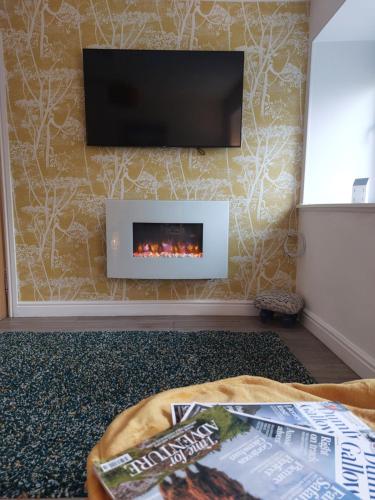 a living room with a tv and a fireplace at Hill Street Cottage in Portpatrick