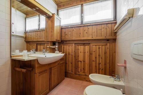 une salle de bain avec un lavabo et des toilettes et des fenêtres dans l'établissement Appartamento Sellaronda, à Arabba