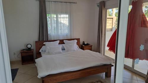 a bedroom with a bed with white sheets and pillows at Aux 2 Métis in Toliara