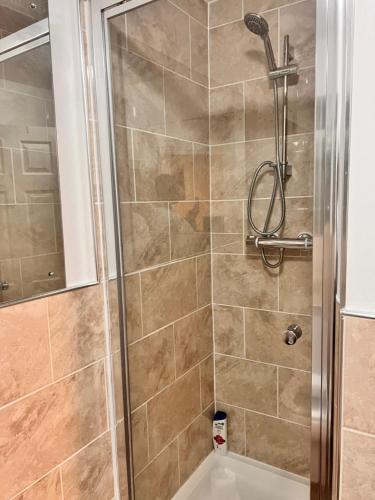 een douche met een glazen deur naast een bad bij Lovely tidy and well decorated en-suite king sized bedroom in a shared 2 bedroom flat in Belle Isle