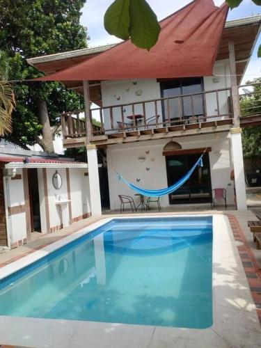 a swimming pool with a hammock in front of a house at Propiedad entera frente al mar con 3 habitaciones in Puerto Cortes