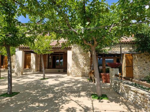a stone house with a dog sitting in front of it at Chambres d'hôtes à Pêtre in Entrevennes