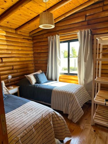 a bedroom with two beds in a log cabin at Cabañas Laguna de los Sauces in Azul