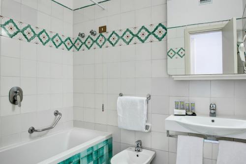 a bathroom with a tub and a sink and a mirror at Imperial Hotel Tramontano in Sorrento