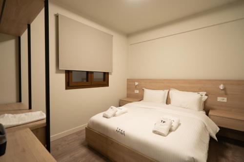 a bedroom with a white bed with towels on it at Thea Petra in Kalabaka
