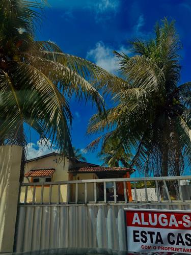 a sign in front of a building with palm trees at Casa de praia in Lucena
