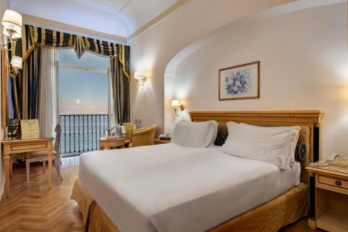 a bedroom with a large white bed and a desk at Imperial Hotel Tramontano in Sorrento