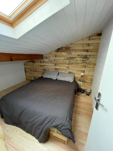 un lit dans une chambre avec un mur en bois dans l'établissement Appt proche plage Capbreton, à Capbreton