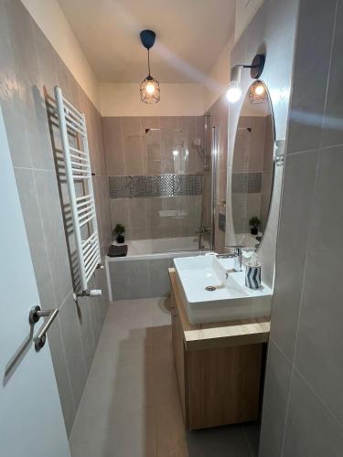 a bathroom with a sink and a tub and a mirror at Victoria Condo Otopeni- Self Check-in and Check- out in Otopeni