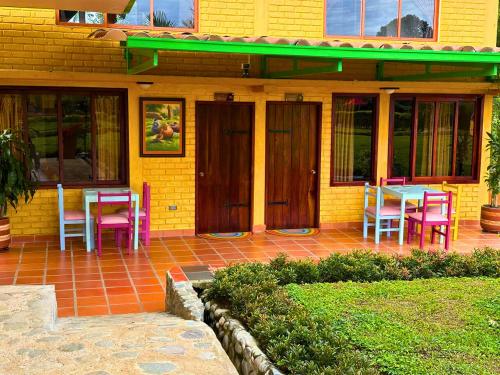 a patio with colorful chairs and a table on a house at El Ensueño Ecohostal & Glamping in Mocoa