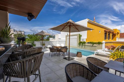 a patio with a table and chairs and an umbrella at Hotel Casa del Gobernador in Cartagena de Indias