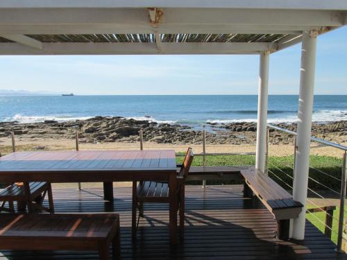 a porch with a table and chairs and the beach at Point Village Accommodation - Hemel op Aarde in Mossel Bay