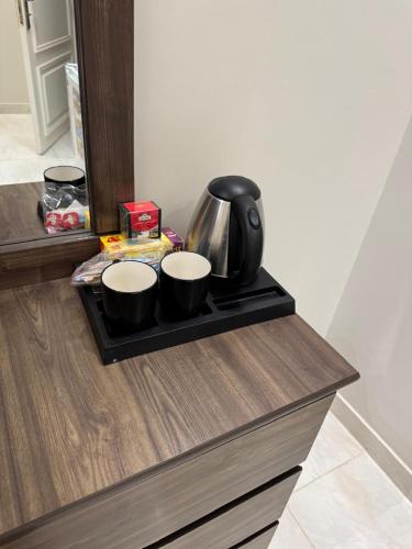 a tray with two cups and a tea kettle on a counter at New Time Apartments in Al-ʿUla